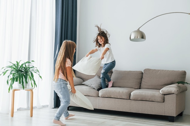 枕を持って走る 昼間は家の部屋で一緒に楽しむ子供たち