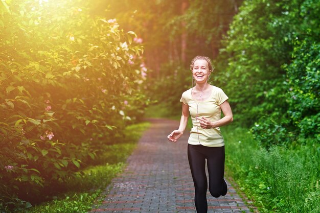 Running woman atletic spotsman trains in the summer park Outdoor fitness portrait after rain