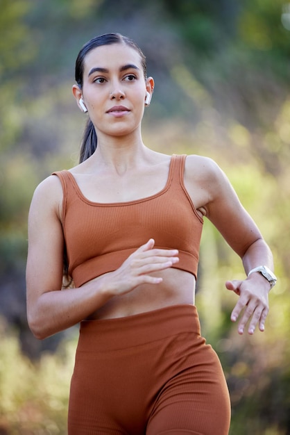 Running woman and outdoor fitness in the forest ready for sports runner workout and walking hike Health wellness training exercise and cardio of an athlete with headphones on a run or speed walk