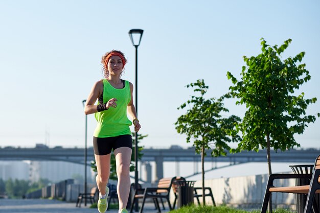 Running woman on the waterfront. Morning jogging. The athlete trains