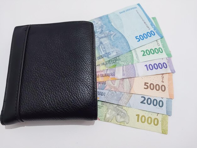 Photo rupiah currency with a black wallet rupiah is the indonesian currency on a white background