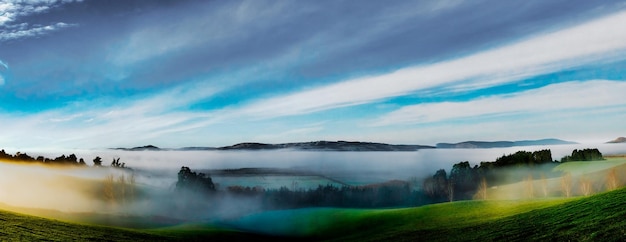 Сельские вооружённые холмы, окутанные слоями низких облаков и тумана