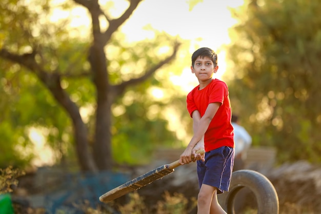 Bambino indiano rurale che gioca cricket