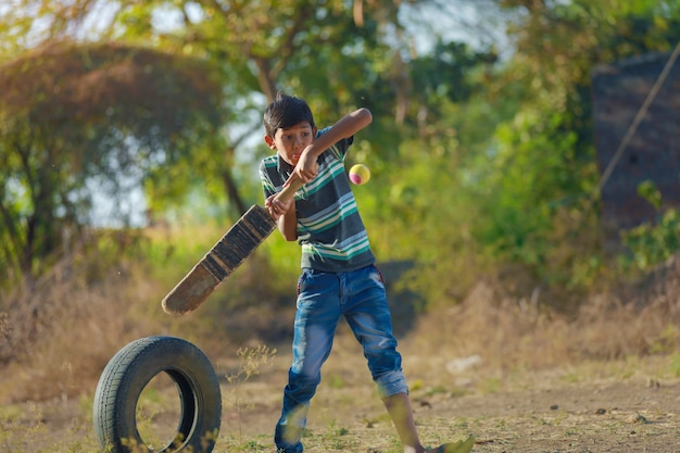 Сельский индийский ребенок играет в крикет
