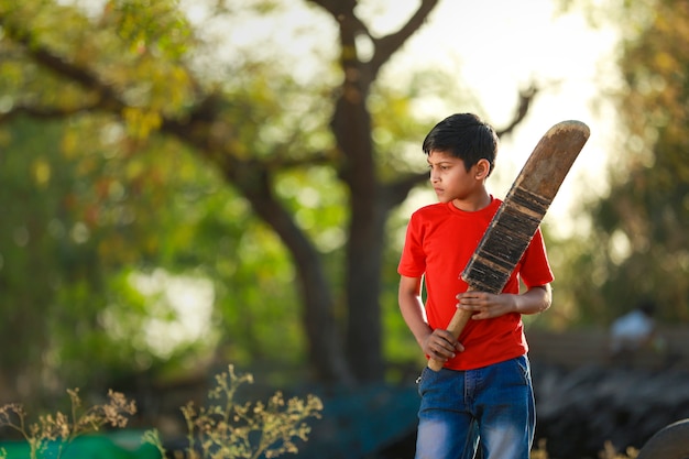 Bambino indiano rurale che gioca cricket