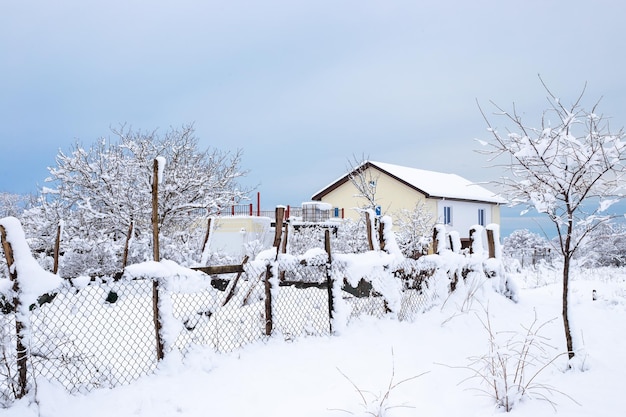 Rural landscape House with a fence covered with snow on a winter day Abundant snowfalls