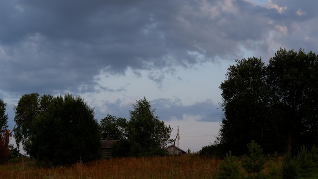 Rural landscape with field at sunset and village in the background Vologda region