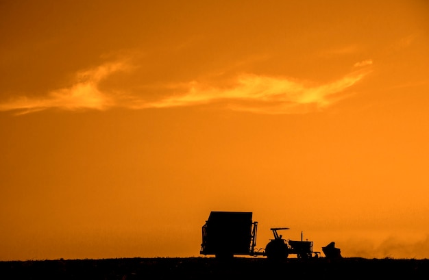 Rural machine working at agriculture field at sunset. Agriculture.
