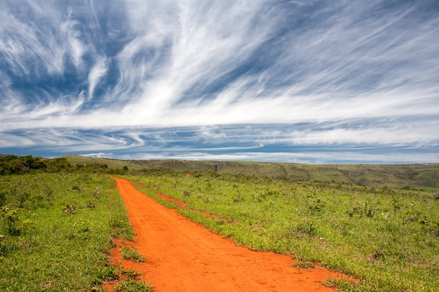 Strada non asfaltata arancio rurale con cielo blu e l'orizzonte lontano