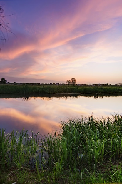 Rural summer sunset landscape with river and dramatic colorful sky