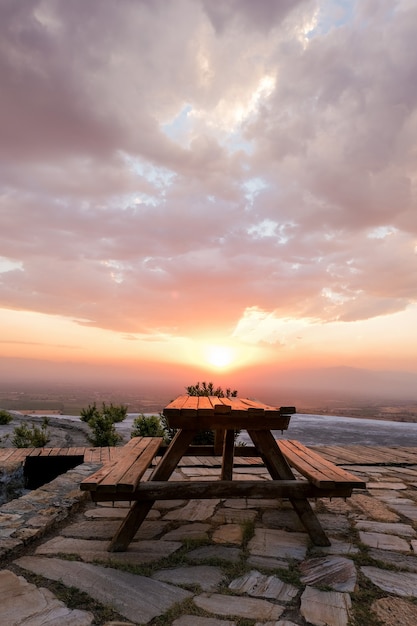 Rural wooden picnic table bench on green grass hill in Hierapolis mountain landscape