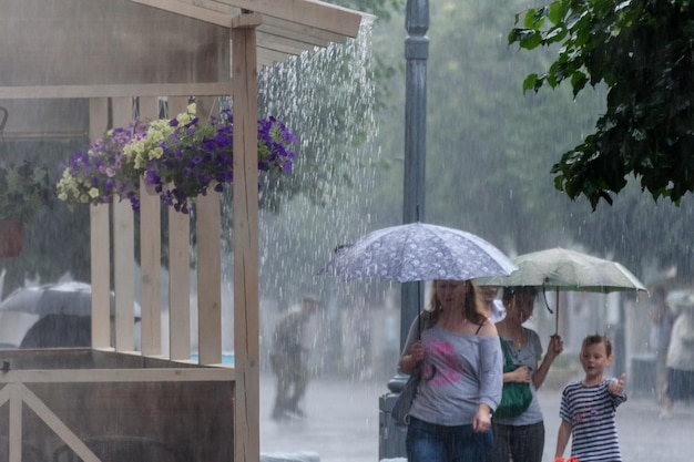 Russia Gatchina July 2018 summer rain in the city and people walking in the rain past a cafe