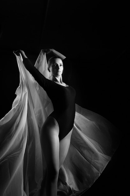 Russia, Moscow, October 1, 2017: Female gymnast posing on a black background and white cloth. Art photo of a female gymnast. Black and white photo