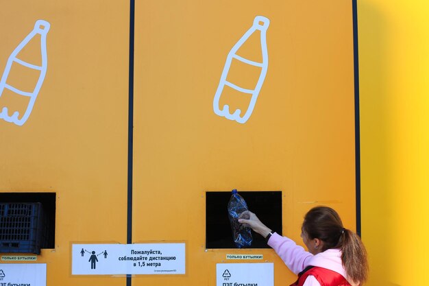 Russia, saint petersburg september 03, 2021: a place for\
sorting waste. a woman throws out garbage strictly by category. the\
inscription division rules. eco-friendly practices in lifesty