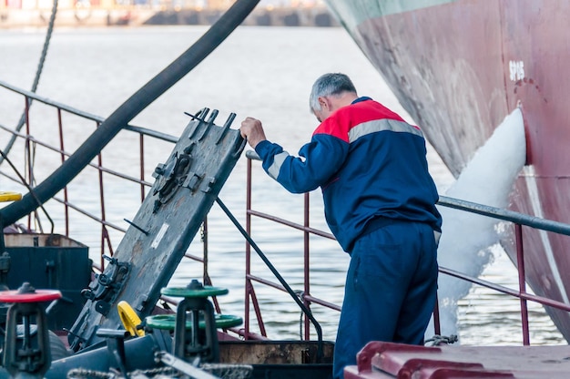 Россия Санкт-Петербург, май 2021 г. Рабочий в морской форме на палубе нефтяного танкера в бухте порта