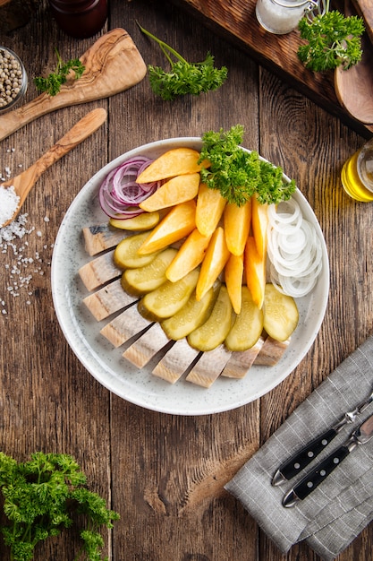 Russian appetizer platter with pickles herring potatoes and onion