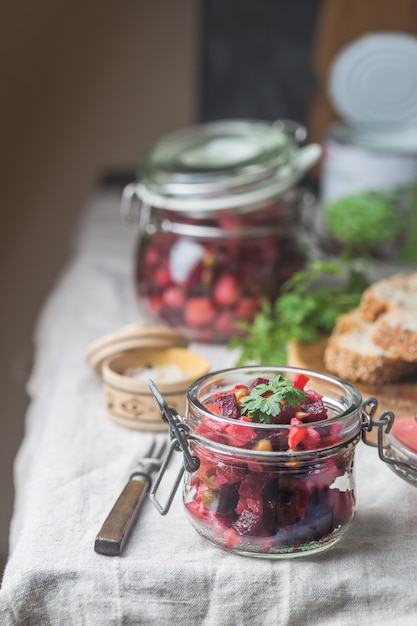 Russian beetroot salad vinaigrette in a glass jar with rye bread, rustic background