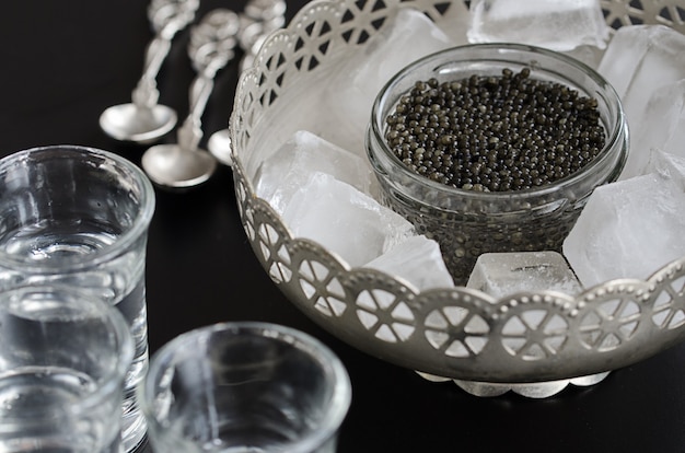 Russian beluga caviar served in silver bowl with ice and alcoholic drink