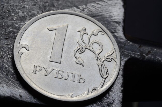 1루블로 표시된 러시아 동전은 긁힌 금속 표면에 빛납니다.