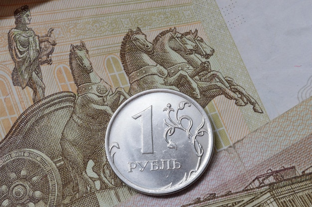 Russian coin with a face value of 1 ruble lies on a banknote Translation of the inscriptions on the coin quot1 rublequot