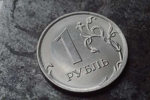 Russian coin with a face value of 1 ruble lies on a dark metal surface closeup