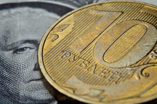 액면가 10루블의 러시아 동전은 미국 종이 달러에 놓여 있습니다.