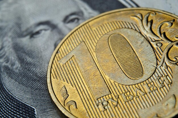 額面 10 ルーブルのロシア硬貨がアメリカの紙幣に横たわっている