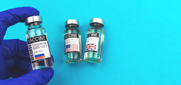 국기가 달린 러시아 COVID-19 코로나바이러스 백신 바이알, 의사 보유 백신, 파란색 장갑, 백신 접종 배너 개념 사진