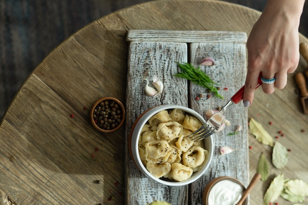 Russian dumplings with sour cream, dill and garlic on a wooden tray