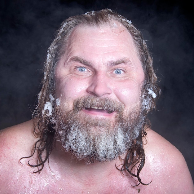 蒸気の雲の中で凍ったひげと髪の毛で雪の中でロシアの極端な裸の男