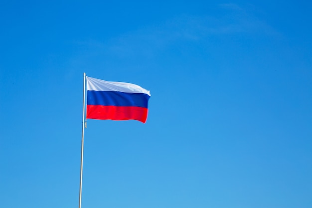 Russian flag on a pole against blue sky copy space