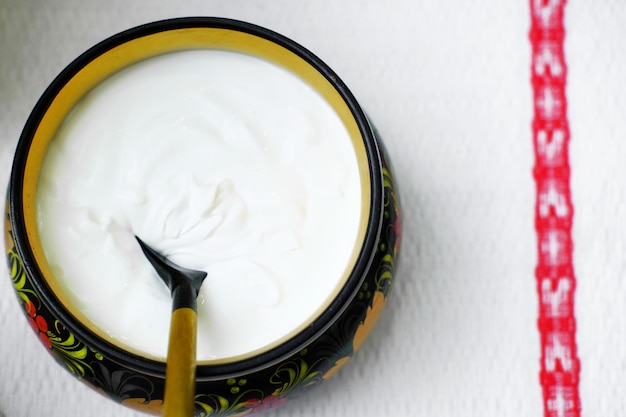 Russian folk Khokhloma dishes with sour cream on the napkin with Slavic pattern