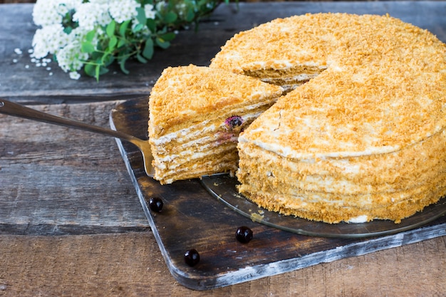 Medovik russo della torta di miele sulla tavola di legno e sul fondo bianco. torta con frutti di bosco torta di ribes