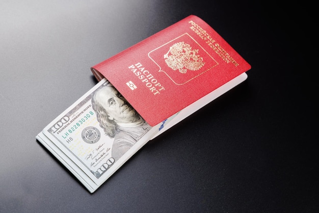 Russian international passport with inserted US dollars on black background