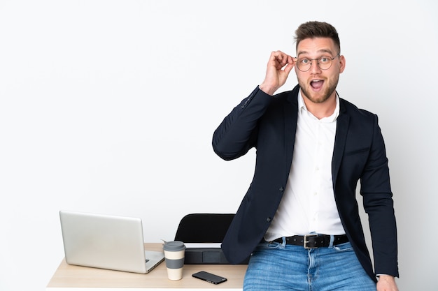 Russian man in an office on white wall with glasses and surprised