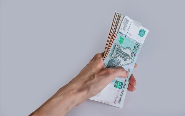 Russian money in a female hand on a gray background.