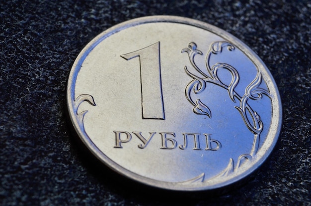 A Russian one ruble coin lies on a dark metal background. close-up.