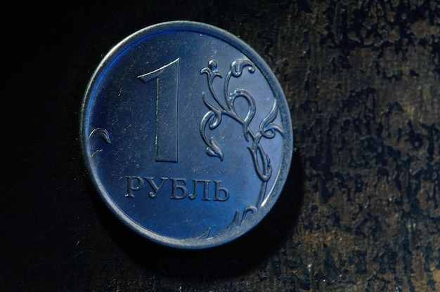 A Russian one ruble coin lies on a dark metal background closeup translation of the text on the coin quot1 rublequot