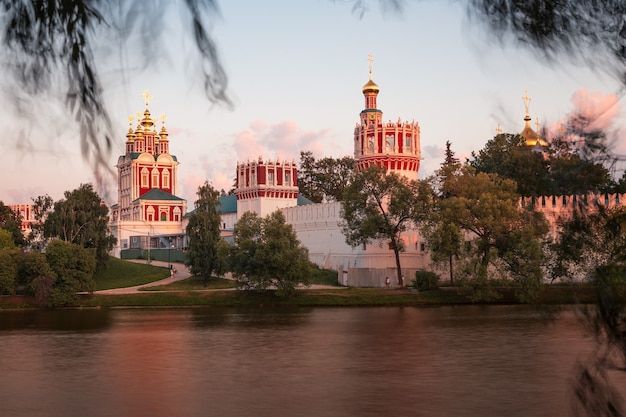 흰색 벽 탑과 교회가 있는 러시아 정교회 수도원이 강 위에 서 있다