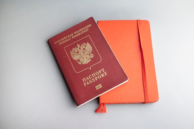 Passaporto russo e taccuino rosso su sfondo grigio