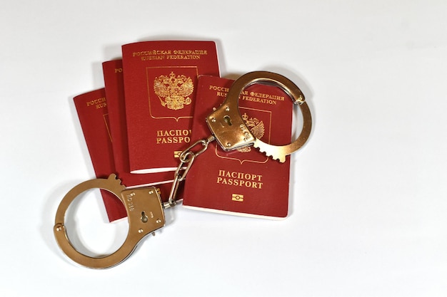 Photo russian passport and handcuffs on white background prohibition of russian citizens on entry and exit passport lock