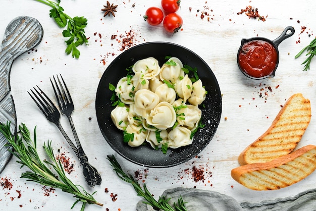 Russian pelmeni meat Dumplings with greens in a black plate Russian traditional cuisine Top view Free copy space