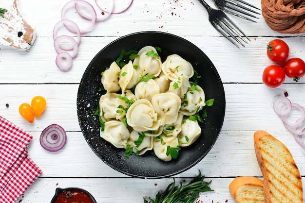 Russian pelmeni meat Dumplings with greens in a black plate Russian traditional cuisine Top view Free copy space