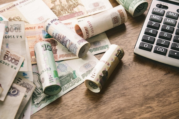 Деньги в российских рублях с калькулятором на фоне деревянного стола для финансовых и инвестиционных концепций