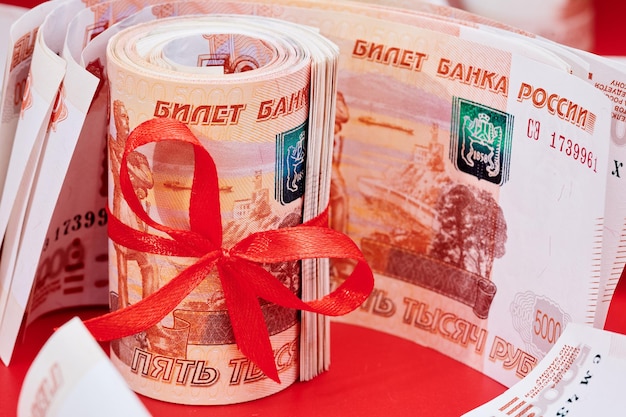 Russian rubles five thousand banknotes bundle of money with red ribbon on red background gift concept