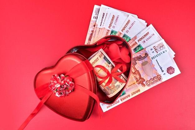 Russian rubles on red background bundle of five thousand banknotes with red ribbon in heart box money gift concept