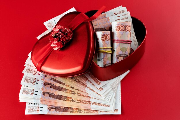 Russian rubles on red background bundle of five thousand banknotes with red ribbon in heart box money gift concept