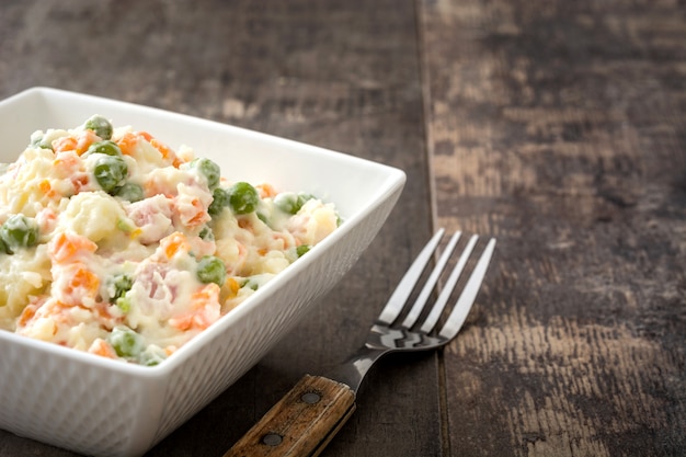 Photo russian salad in bowl on a rustic wooden table