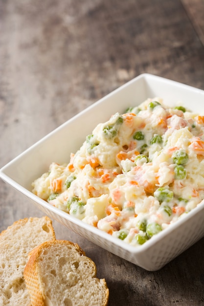 Russian salad in bowl on a rustic wooden table