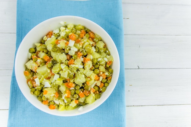 Russian salad Olivier with potato carrot green peas on white background